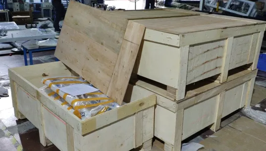 Packing example from the documented shipping process: protective wrapping and wooden crates before closure. The actual crate arrangement depends on the equipment.